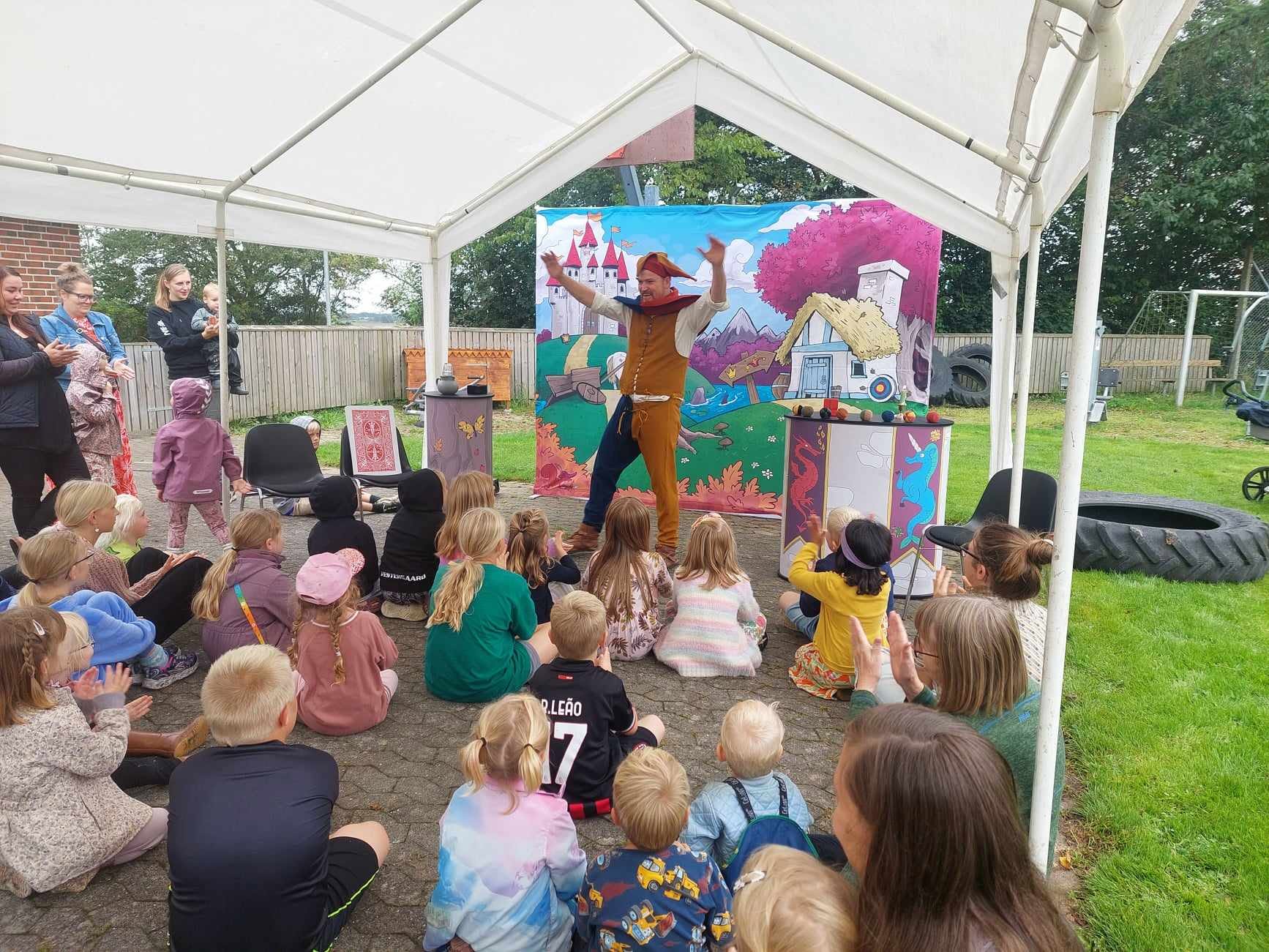 Børn og forældre sidder under et telt og ser Gøgleren fra Sherwood til byfest
